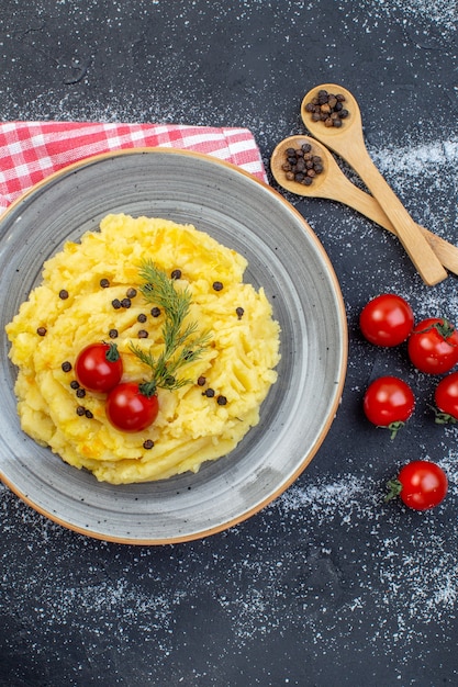 Sopra la vista della farina di patate servita con pomodori aneto pepe su asciugamano rosso spogliato su sfondo bianco nero misto colore