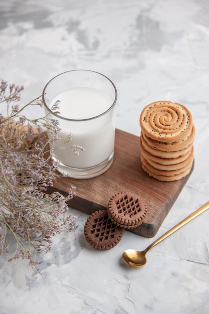 Sopra la vista della tazza di vetro piena di latte e biscotti sulla tavola di legno su fondo di colori pastello