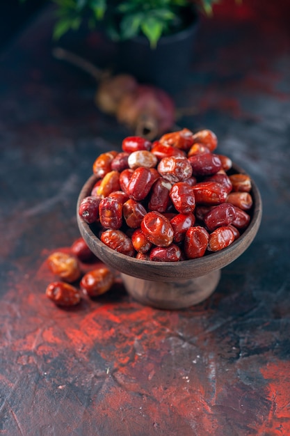 Sopra la vista di frutti freschi di silverberry crudi all'interno e all'esterno di una ciotola di legno e di un vaso di fiori su uno sfondo di colori misti