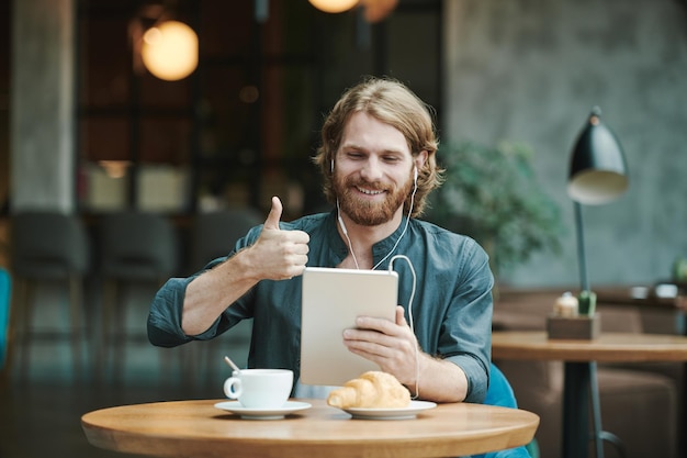 Sopra la vista di un uomo irriconoscibile che scatta foto di caffè nero e croissant sul tavolo nel blogger del caffè