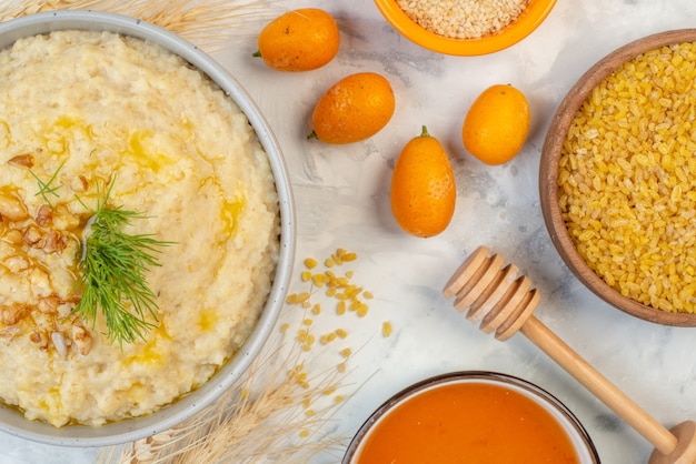 Sopra la vista di una deliziosa colazione con avena, riso integrale, kumquat fresco, miele, cucchiaio di legno su fondo di ghiaccio