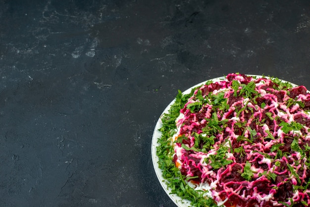 Sopra la vista di una deliziosa insalata decorata con verde in un piatto bianco sul lato sinistro su sfondo nero con spazio libero