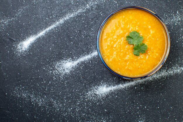 Sopra la vista di una deliziosa zuppa di lenticchie rosse in una ciotola servita con verdure su sfondo bianco nero con spazio libero