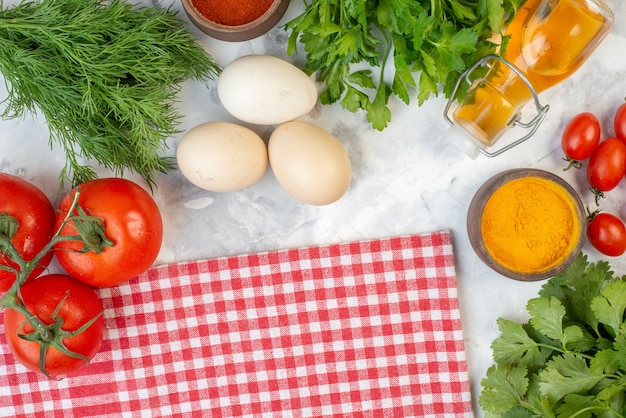 Sopra la vista di verdure fresche zenzero giallo caduto olio bottiglia verde fasci pomodori con steli asciugamano rosso spogliato