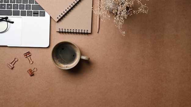 Sopra la vista notebook tazza di caffè e computer portatile su sfondo marrone