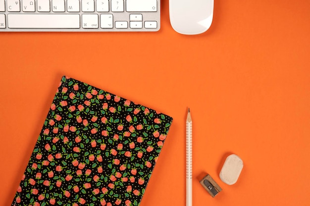 Sopra scrivania da ufficio arancione con tastiera e mouse del computer portatile