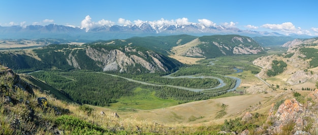 Sopra una pittoresca valle di montagna con un fiume, soleggiata mattina d'estate, vista panoramica