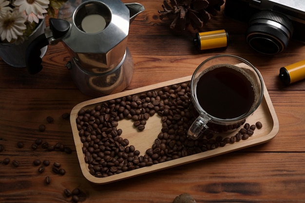 Sopra vista tazza di caffè, chicchi di caffè tostati e moka sul tavolo di legno.