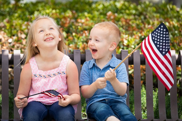 Sorella e fratello che si confrontano la taglia della bandiera americana sulla panchina del parco