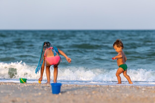 Sorella maggiore che gioca con il fratello minore incagliato vicino alla riva durante le vacanze estive