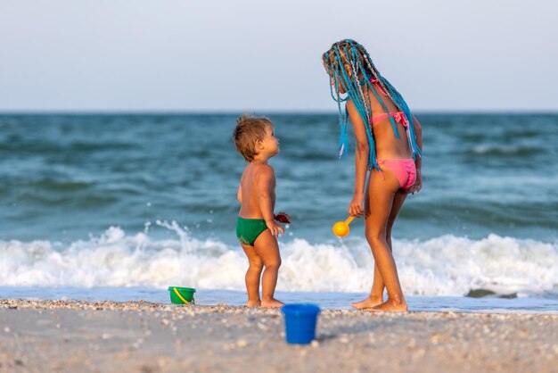 Sorella maggiore che gioca con il fratello minore incagliato vicino alla riva durante le vacanze estive