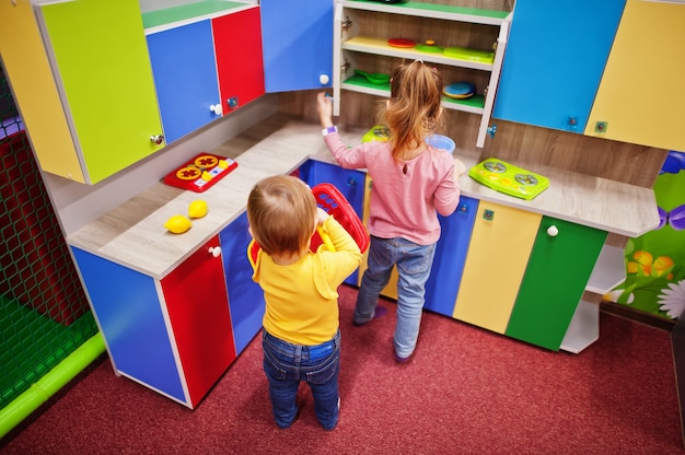 Sorelle carine che giocano nel centro giochi al coperto. Asilo nido o sala giochi in età prescolare. Nella cucina dei bambini.