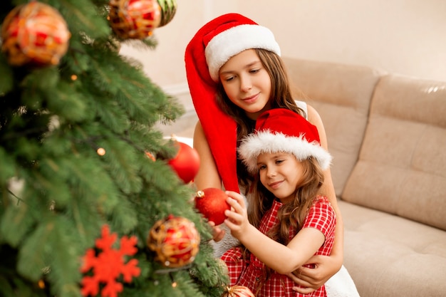 sorelle che decorano l'albero di Natale a casa