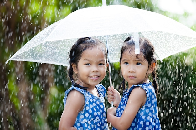 Sorelle con ombrello divertirsi giocando sotto la pioggia