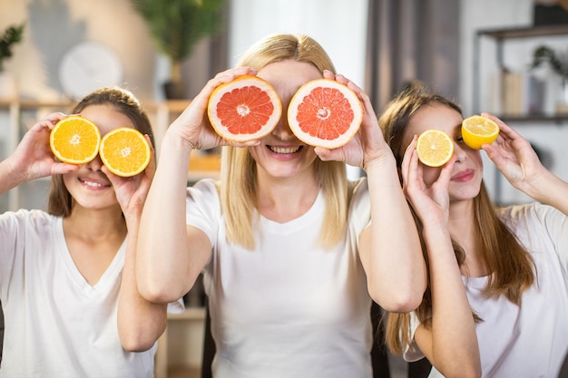 Sorelle e madre che coprono gli occhi sotto fette di agrumi