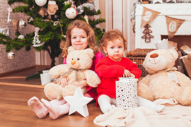 Sorelle graziose felici che si siedono nella stanza decorata di Natale