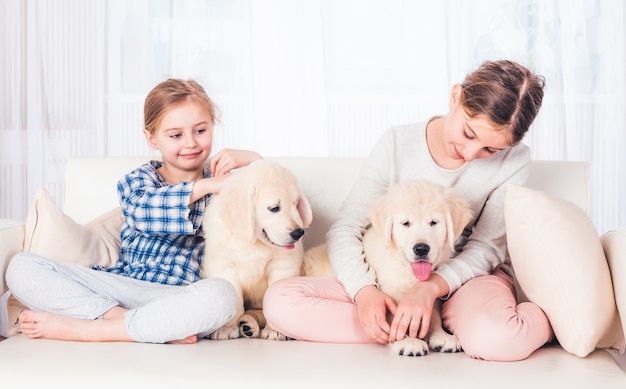 Sorelle sorridenti che si siedono con i cuccioli