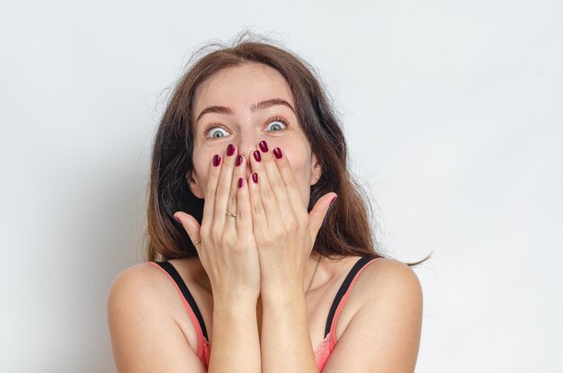 Sorpresa donna dai capelli scuri si copre la bocca con le mani grandi occhi grigi sopracciglia nere