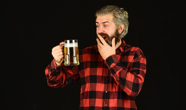 Sorpreso birraio brutale hipster bere birra maturo uomo barbuto tenere birra boccale di vetro di alcol bevanda fiducioso barista barman nel bar che riposa al pub Cheers sport bar cercando una nuova birra