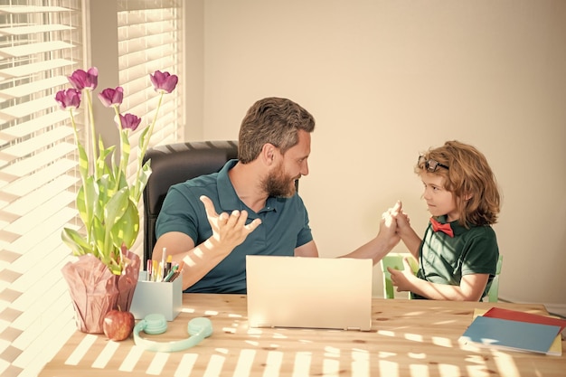 Sorpreso padre e figlio usano il computer a casa famiglia e ragazzo blog genitorialità fanno i compiti