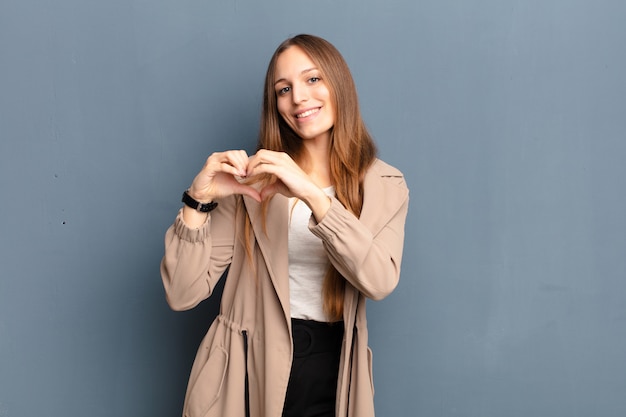 sorride e si sente felice, carino, romantico e innamorato, facendo a forma di cuore con entrambe le mani