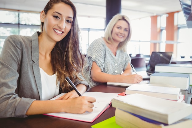 Sorride matura gli studenti delle femmine che scrivono le note allo scrittorio