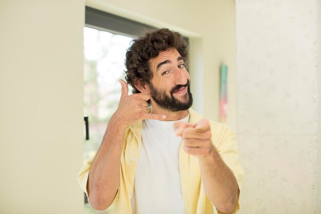 Sorridendo allegramente e indicando la telecamera mentre fai una chiamata tu più tardi gesto parlando al telefono