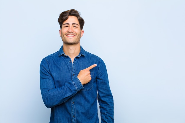 sorridendo allegramente, sentendosi felice e indicando il lato e verso l'alto, mostrando l'oggetto nello spazio della copia