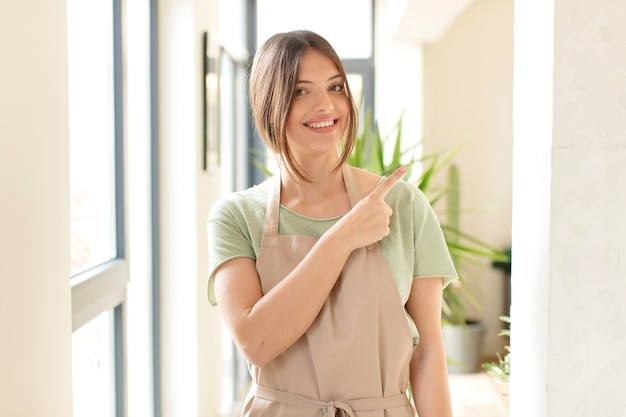 sorridendo allegramente, sentendosi felice e indicando il lato e verso l'alto, mostrando l'oggetto nello spazio della copia