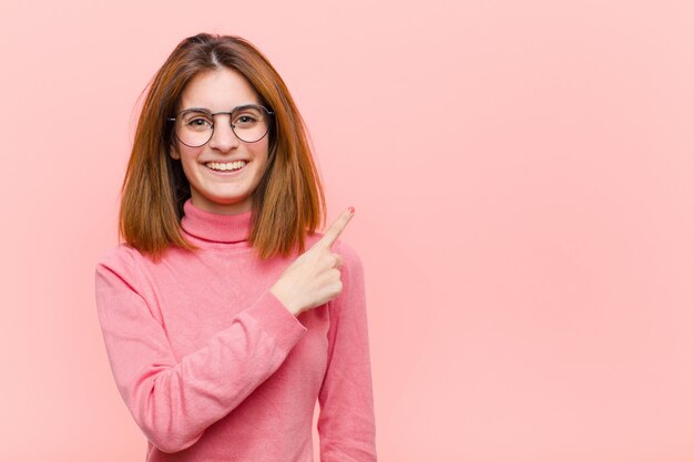 sorridendo allegramente, sentendosi felice e indicando il lato e verso l'alto, mostrando l'oggetto nello spazio della copia