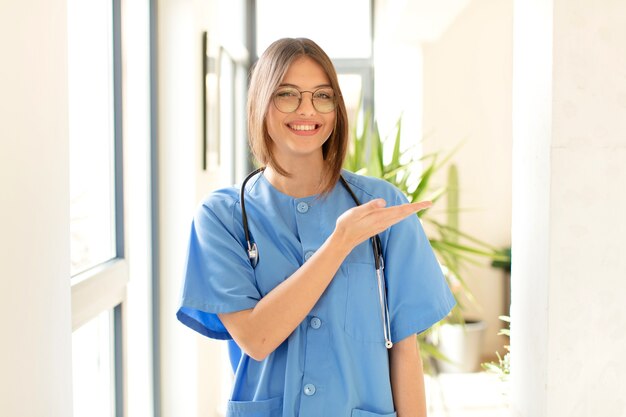 sorridendo allegramente, sentendosi felice e mostrando un concetto nello spazio della copia con il palmo della mano