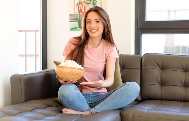 sorridendo allegramente, sentendosi felice e mostrando un concetto nello spazio della copia con il palmo della mano