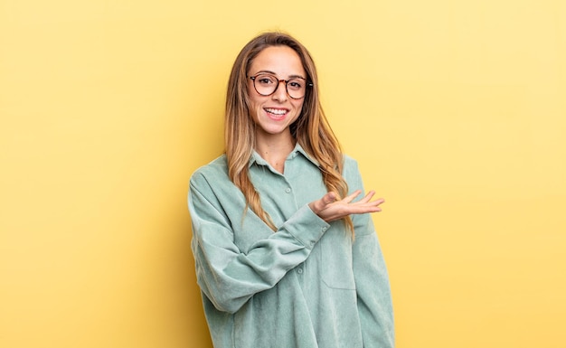 sorridendo allegramente sentendosi felice e mostrando un concetto nello spazio della copia con il palmo della mano