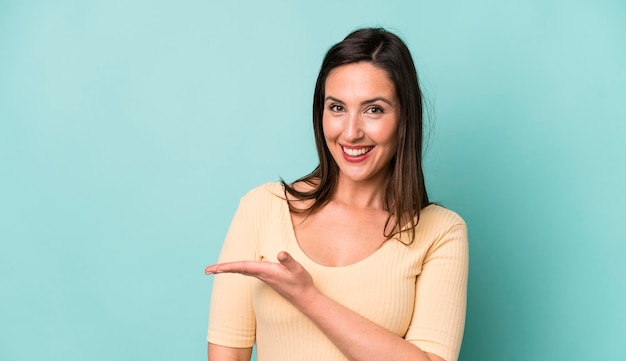 sorridendo allegramente sentendosi felice e mostrando un concetto nello spazio della copia con il palmo della mano