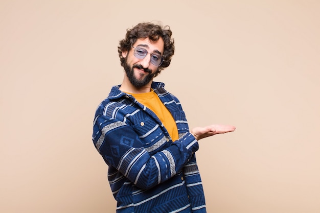 sorridendo allegramente, sentendosi felice e mostrando un concetto nello spazio della copia con il palmo della mano