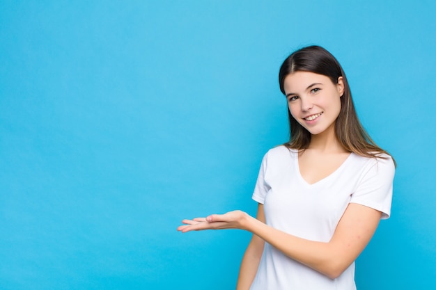 sorridendo allegramente, sentendosi felice e mostrando un concetto nello spazio della copia con il palmo della mano