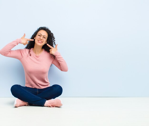 sorridendo con fiducia indicando il proprio ampio sorriso, atteggiamento positivo, rilassato, soddisfatto