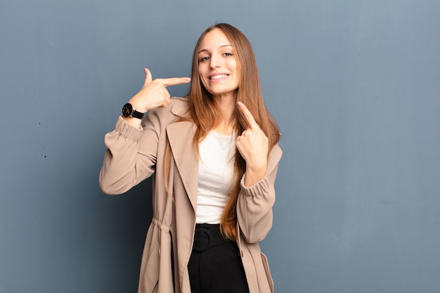 sorridendo con fiducia indicando il proprio ampio sorriso, atteggiamento positivo, rilassato, soddisfatto