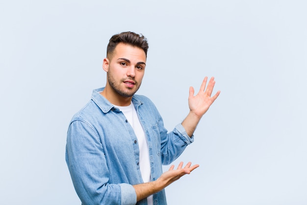 sorridendo con orgoglio e sicurezza, sentendosi felice e soddisfatto e mostrando un concetto sullo spazio della copia