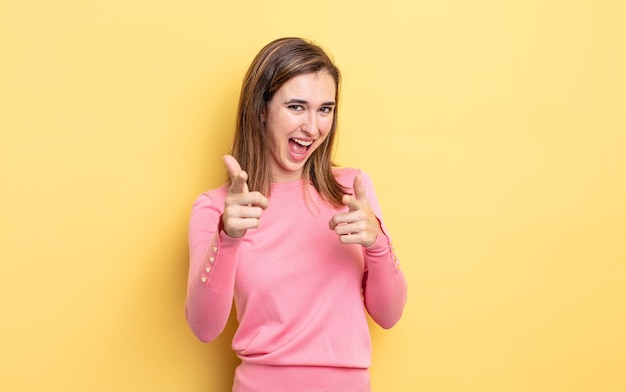 Sorridendo con un atteggiamento felice positivo positivo che punta alla telecamera facendo segno di pistola con le mani