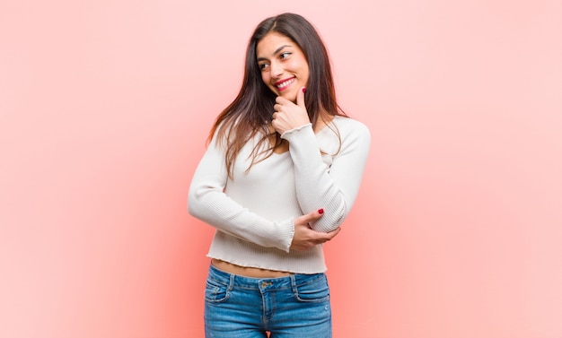 sorridendo con un'espressione felice e fiduciosa con la mano sul mento, chiedendosi e guardando di lato