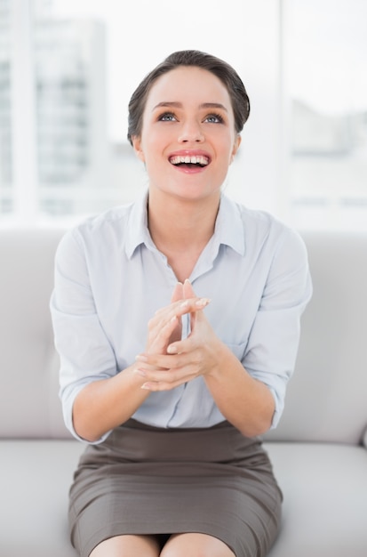 Sorridendo donna ben vestita che applaude mentre alzando lo sguardo