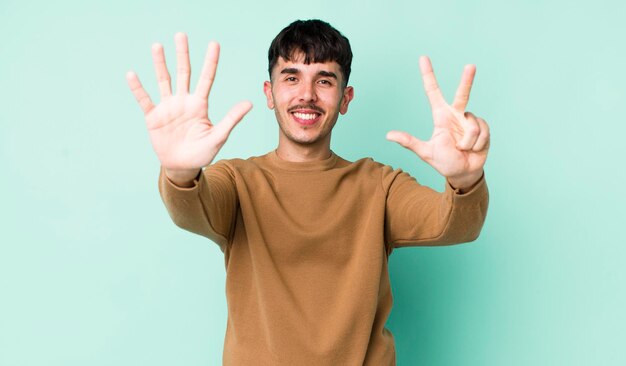 Sorridendo e guardando amichevole che mostra il numero otto o ottavo con il conto alla rovescia della mano in avanti