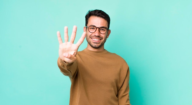 Sorridendo e guardando amichevole che mostra il numero quattro o quarto con il conto alla rovescia della mano in avanti