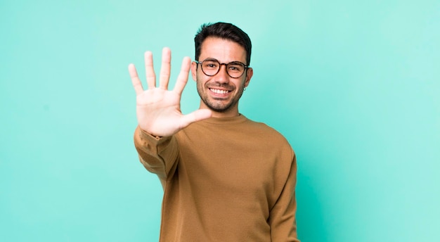 sorridendo e guardando amichevole mostrando il numero cinque o quinto con il conto alla rovescia in avanti della mano