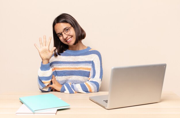 sorridendo e guardando amichevole, mostrando il numero cinque o quinto con la mano in avanti, conto alla rovescia