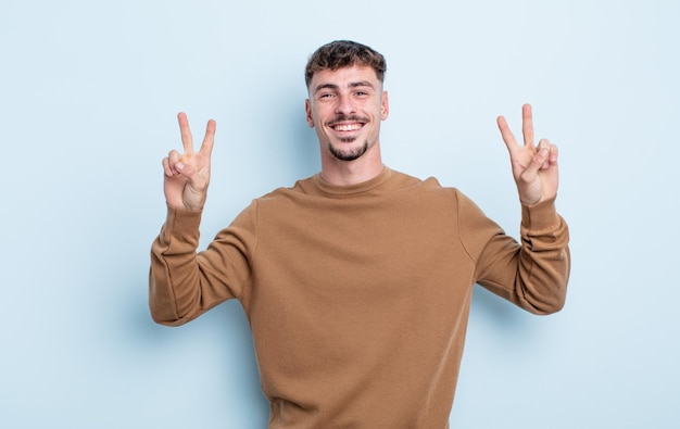 Sorridendo e guardando felice, amichevole e soddisfatto, gesticolando vittoria o pace con entrambe le mani