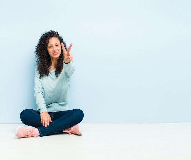 sorridendo e sembrando felice, spensierato e positivo, gesticolando vittoria o pace con una mano