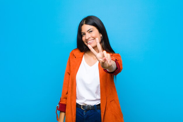 sorridendo e sembrando felice, spensierato e positivo, gesticolando vittoria o pace con una mano