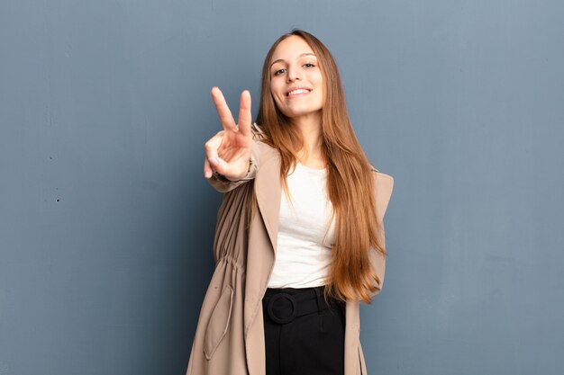 sorridendo e sembrando felice, spensierato e positivo, gesticolando vittoria o pace con una mano